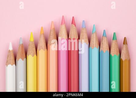 Farbige Bleistifte in Pastelltönen auf pinkfarbenem Hintergrund. Mehrfarbige Pastellstifte. Stockfoto