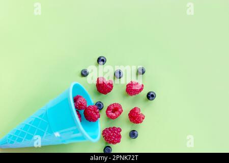 Waffelsüße Eiscreme mit Himbeeren auf weißem Holzhintergrund, Draufsicht. Flach liegend. Kreatives Speisenkonzept mit farbenfrohen Kegeln auf Pastellfarben Stockfoto