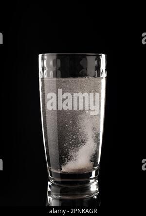 Brausepillen. Glas mit Flüssigkeit in Blasen auf schwarzem Hintergrund. Aspirin. Tablette mit Vitaminen Stockfoto