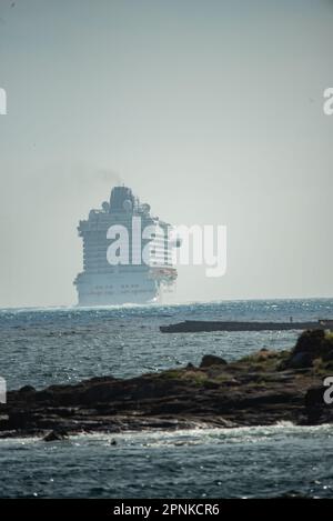 Vigo, Spanien. April 19., 2023. Das luxuriöse Kreuzfahrtschiff Britannia von southampton segelt in den Südkanal der Bucht von Vigo und setzt Kurs nach lissabon mit seiner 330 Meter Länge und seinen fast 7000 Passagieren und der Besatzung an Bord. Das Schiff wurde von zwei Patrouillenbooten der staatlichen Sicherheitskräfte auf die Cies-Inseln begleitet. Kredit: Xan Gasalla / Alamy Live News. Stockfoto