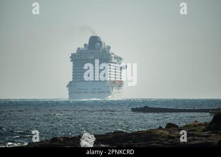 Vigo, Spanien. April 19., 2023. Das luxuriöse Kreuzfahrtschiff Britannia von southampton segelt in den Südkanal der Bucht von Vigo und setzt Kurs nach lissabon mit seiner 330 Meter Länge und seinen fast 7000 Passagieren und der Besatzung an Bord. Das Schiff wurde von zwei Patrouillenbooten der staatlichen Sicherheitskräfte auf die Cies-Inseln begleitet. Kredit: Xan Gasalla / Alamy Live News. Stockfoto