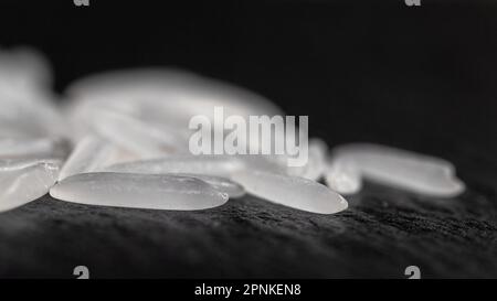 Weißer Reis auf einer schwarzen Graphitsteinplatte, gesundes Essen Stockfoto
