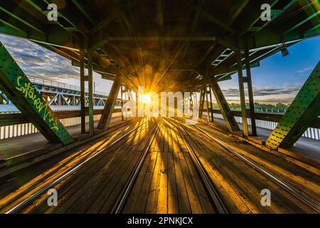 Warschau, Polen - 2022. Juli: Lange Gdanski-Brücke aus Holz und Metall mit Straßenbahnschienen und grünem Dach am Morgen zur goldenen Stunde bei Sonnenaufgang Stockfoto