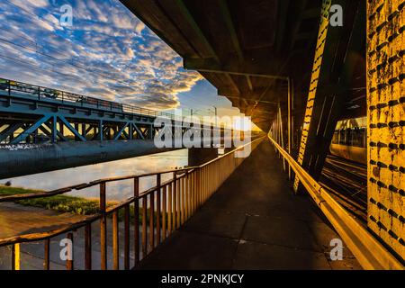 Warschau, Polen - 2022. Juli: Lange Gdanski-Brücke aus Holz und Metall mit Straßenbahnschienen und grünem Dach am Morgen zur goldenen Stunde bei Sonnenaufgang Stockfoto