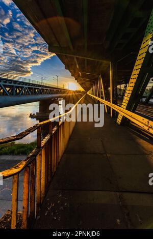 Warschau, Polen - 2022. Juli: Lange Gdanski-Brücke aus Holz und Metall mit Straßenbahnschienen und grünem Dach am Morgen zur goldenen Stunde bei Sonnenaufgang Stockfoto