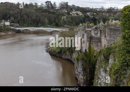 Chepstow, Großbritannien. 14. April 2023. Der Fluss Wye und die Old Wye Bridge werden vom Schloss Chepstow aus gesehen. Chepstow Castle befindet sich über den Klippen am Fluss Wye und ist die älteste noch existierende poströmische Steinbefestigung in Großbritannien. Die Old Wye Bridge (1816) ist die weltweit größte Eisenbogen-Straßenbrücke aus den ersten 50 Jahren des Eisen- und Stahlbaus. Kredit: Mark Kerrison/Alamy Live News Stockfoto