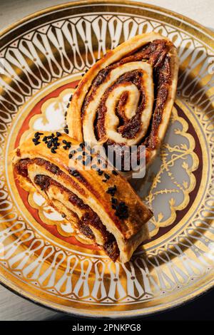 Kleicha, irakische Datteln Kekse in spiralförmiger Form mit Nigellasamen auf einer kunstvoll verzierten goldenen Platte Stockfoto