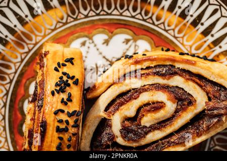 Kleicha, irakische Datteln Kekse in spiralförmiger Form mit Nigellasamen auf einer kunstvoll verzierten goldenen Platte Stockfoto