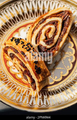 Kleicha, irakische Datteln Kekse in spiralförmiger Form mit Nigellasamen auf einer kunstvoll verzierten goldenen Platte Stockfoto