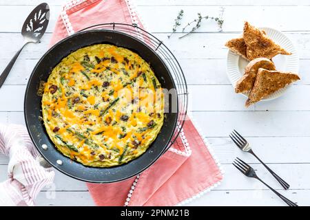 Hausgemachter Speck und Spargelfrittata, garniert mit Käse und serviert mit Toast Stockfoto