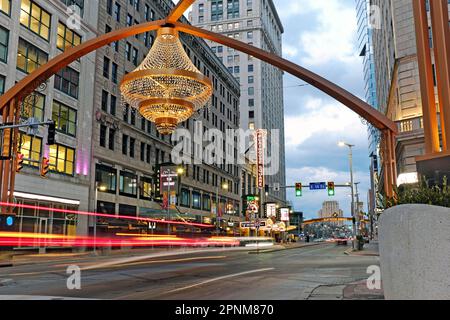 Abenddämmerung entlang der Euclid Avenue im Playhouse Square Theater District in Cleveland, Ohio, USA am 27. Februar 2023. Der riesige Kronleuchter im Freien, der größte Kronleuchter im Freien der USA, schwebt über der Kreuzung von Euclid Avenue und East 14. Street. Das Theaterviertel ist das zweitgrößte Zentrum für darstellende Künste in den USA. Stockfoto