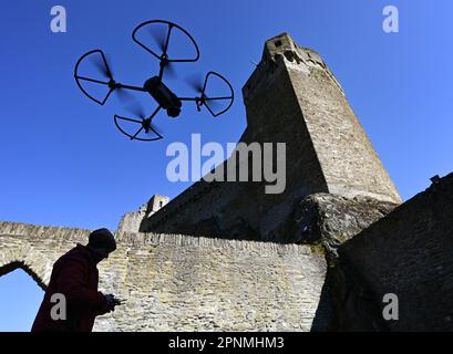 PRODUKTION - 05. April 2023, Hessen, Hohenstein: Werner Maziborsky von der Firma Linsinger ZT aus St. Johann im Pongau (Österreich) startet eine Drohne, um die Burgruinen Hohenstein in der Nähe von Bad Schwalbach im Taunus digital zu untersuchen. Der Landesbetrieb Bau und Immobilien Hessen (LBIH) hat am Kulturdenkmal im Aartal bereits einen großen Teil eines umfangreichen Renovierungsprojekts durchgeführt. Für die nächsten Restaurierungsschritte muss der Burgkomplex in diesem Frühjahr digital überprüft werden. (Zu dpa: 'Moderne Technologie trifft auf alte Mauern - Schlossbesichtigung mit der Drohne'. Foto: Arne Dedert/dpa Stockfoto