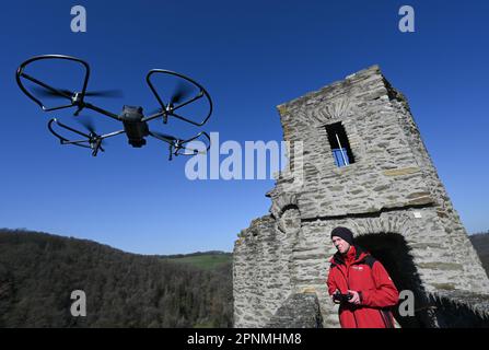 PRODUKTION - 05. April 2023, Hessen, Hohenstein: Werner Maziborsky von der Firma Linsinger ZT aus St. Johann im Pongau (Österreich) startet eine Drohne auf den Festungsmauern, um die Burgruinen Hohenstein in der Nähe von Bad Schwalbach im Taunus digital zu besichtigen. Der Landesbetrieb Bau und Immobilien Hessen (LBIH) hat am Kulturdenkmal im Aartal bereits einen großen Teil eines umfangreichen Renovierungsprojekts durchgeführt. Für die nächsten Restaurierungsschritte muss der Burgkomplex in diesem Frühjahr digital überprüft werden. (Zu dpa: 'Moderne Technologie trifft auf alte Mauern - Schlossbesichtigung mit der Drohne'. Foto: A Stockfoto