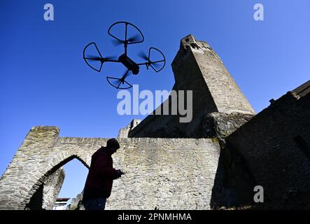 PRODUKTION - 05. April 2023, Hessen, Hohenstein: Werner Maziborsky von der Firma Linsinger ZT aus St. Johann im Pongau (Österreich) startet eine Drohne, um die Burgruinen Hohenstein in der Nähe von Bad Schwalbach im Taunus digital zu untersuchen. Der Landesbetrieb Bau und Immobilien Hessen (LBIH) hat am Kulturdenkmal im Aartal bereits einen großen Teil eines umfangreichen Renovierungsprojekts durchgeführt. Für die nächsten Restaurierungsschritte muss der Burgkomplex in diesem Frühjahr digital überprüft werden. (Zu dpa: 'Moderne Technologie trifft auf alte Mauern - Schlossbesichtigung mit der Drohne'. Foto: Arne Dedert/dpa Stockfoto