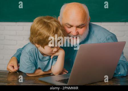 Ein Junge macht seine Schulaufgaben mit seinem Vater. Alte Lehrerin. Ich liebe unsere Momente in der Schule - erinnere dich an die Zeit. Bildungs- und Unterrichtskonzept. Stockfoto