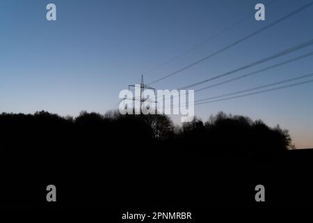 Blauer Abendhimmel in einer Landschaft mit Bäumen und einem Kraftmast Stockfoto