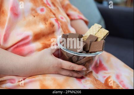 Nahaufnahme einer fetten Frau, die eine Schüssel Schokolade hält und auf dem Sofa sitzt Stockfoto