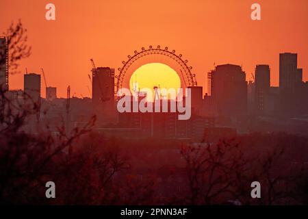 London, Großbritannien. 19. April 2023. UK Weather: Dramatische Abendsonne geht hinter dem Riesenrad des London Eye unter, vom Gipfel des Greenwich Park aus gesehen. Kredit: Guy Corbishley/Alamy Live News Stockfoto