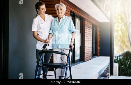 Stetige Fortschritte auf dem Weg zu einer vollständigen Erholung. Eine Krankenschwester, die einem Seniorenpatienten außerhalb eines Altenheims assistiert. Stockfoto