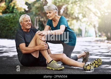 Wir müssen das von einem Profi überprüfen lassen. Ein älterer Mann, der eine Verletzung erlitt, während er mit seiner Frau joggte. Stockfoto