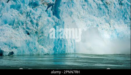 Spektakuläres Gletscherkalben. Eiswürfel fielen ins Wasser wie eine Explosion. Felsen, Eis, Flüsse, Wälder und Berge: Die Sommerlandschaft von Alaska. Stockfoto
