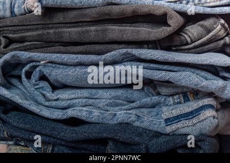 Abstrakter Jeanenstapel. Hintergrund Mode Jeans strukturiert verschiedene Farbtöne Denim. Leinwand Denim Textur. Blaues Denim Closeup Stockfoto