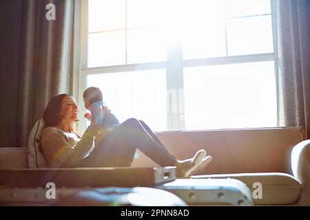 Es geht nichts über eine Liebe von Müttern. Eine junge Frau, die sich mit ihrem kleinen Jungen zu Hause auf dem Sofa anfreundet. Stockfoto