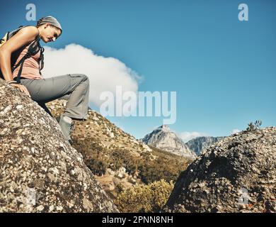 Auf dem Weg in größere Höhen. Eine junge Frau, die über Felsen klettert, während sie durch die Berge wandert. Stockfoto