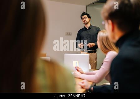 Blick von Schulter zu männlichem Leiter des Business Teams Präsentation des Projektplans für multiethnische Gruppen, Erläuterung von Aufgaben, Vortrag am Tisch bei der Besprechung. Stockfoto