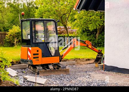 Ein kleiner orangefarbener Bulldozer für mobile Bagger in der Nähe eines Privathauses Stockfoto