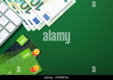 LONDON, UK - 15. NOVEMBER 2022: SEB-bankkreditkarte mit Tastatur und hundert Euro-Banknoten auf Grün. Draufsicht. Stockfoto