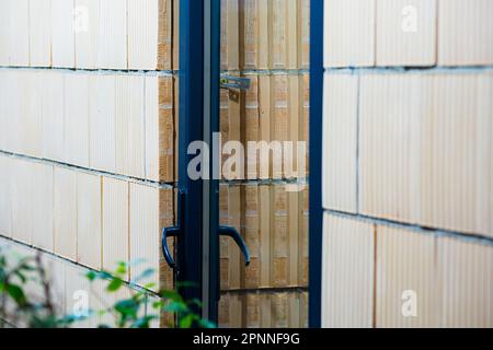 Verstärkte Kunststofftür aus Glas. Porenbetonsteinwand. Stockfoto