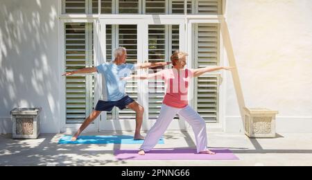 Alter ist nichts als eine Zahl. Ein langes Bild eines Seniorenpaares, das zu Hause Yoga praktiziert. Stockfoto