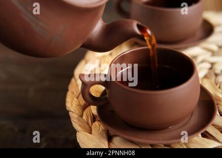 Teezeremonie. Traditionelles Asiatisches Teeutensil, Serviert Authentisches Set. Person, die Tee von der Teekanne aus brauner Keramik bis zur Teekanne einschenkt. Bambusschale. Lifestyle. Wir Stockfoto