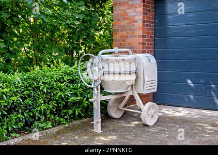 Ein weißer alter Betonmischer in der Nähe des Garageneingangs. Stockfoto