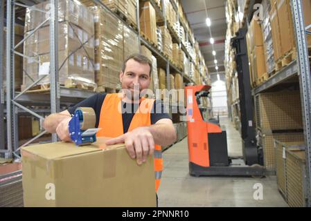 Arbeiter in einem Warenlager im Einzelhandel verpackten ein Paket mit Klebeband Stockfoto