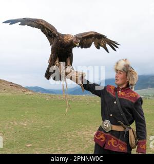 Issyk Kul, Kirgisistan - Mai 2022: Adlertrainer und sein Goldadler, der Adler zum Jagen trainiert, mit traditionellen, weitergegebenen Techniken Stockfoto