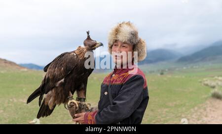 Issyk Kul, Kirgisistan - Mai 2022: Adlertrainer und sein Goldadler, der Adler zum Jagen trainiert, mit traditionellen, weitergegebenen Techniken Stockfoto