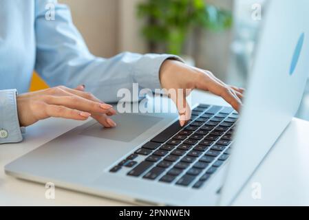 Nahaufnahme der Hände einer Geschäftsfrau mit einem Laptop, der auf der Tastatur tippt, nach Informationen sucht, surft. Studentin für Managerpraktikum Stockfoto