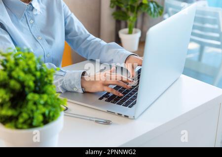 Junge Frau, die im Büro an einem Laptop arbeitet. Praktikantin für Banker oder Manager. Junge Geschäftsfrau an ihrem Arbeitsplatz Stockfoto