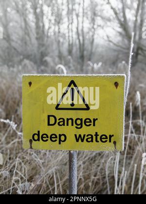 Ein gelbes Schild, das an einem Pfosten befestigt ist, umgeben von einer Decke aus weißem Schnee. Stockfoto