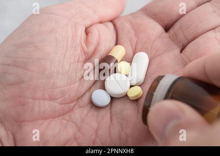Mann, der verschiedene Medizinpillen und Tabletten einnimmt. Medikamentendosis für den Behandlungsverlauf der männlichen Handfläche. Schließen. Medikamente, Gesundheitsversorgung, Behandlungskonzept Stockfoto