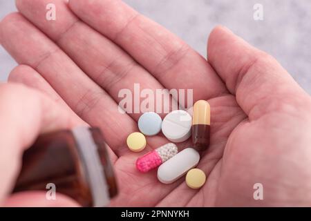 Mann, der verschiedene Arzneimittel-Pillen, Kapseln und Tabletten einnimmt. Medikamentendosis für den Behandlungsverlauf der männlichen Handfläche. Schließen. Medikamente, Gesundheitsfürsorge, Treatment Stockfoto