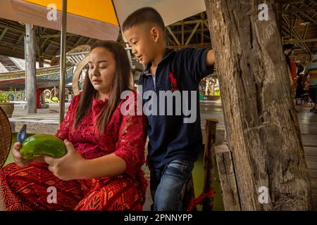 Mutter und Sohn bereiten Essen auf dem schwimmenden Markt in Pattaya, Thailand zu Stockfoto