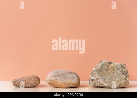 Eine Reihe von drei Steinen, von der kleinsten bis zur größten, leeren Fläche angeordnet. Stockfoto