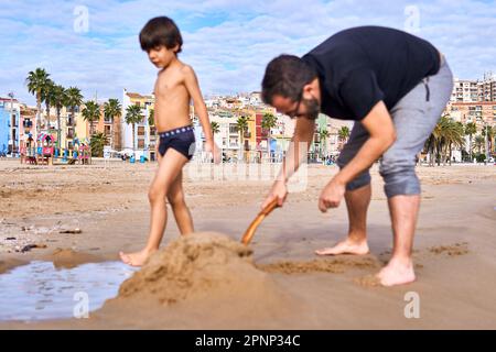 Villajoyosa Spanien farbenfrohe Häuser und Promenade mit Vater und Sohn, die am Strand vor dem Hotel spielen Stockfoto