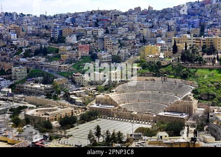 Ansicht der Stadt und des Römischen Theaters, Amman, Königreich Jordanien  Erhöhte Ansicht des Römischen Theaters in Amman, Jordanien, fotografiert von den Hügelruinen der Zitadelle von Amman mit der modernen Stadtlandschaft, die sich im Hintergrund ausbreitet. Amman, Jordanien (Römische Philadelphia) ist für die meisten ausländischen Besucher das Highlight von Amman. Das Theater selbst ist in die Nordseite eines Hügels geschnitten und bietet Platz für 6000 Zuschauer. 2. Jahrhundert n. Chr. während der Herrschaft von Antoninus Pius (138–161 n. Chr.) , Stockfoto