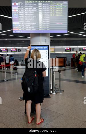 Stehende Frau, die sich die Abfahrts- und Ankunftszeiten auf den CRT-Monitoren ansieht. Phnom Penh. Kambodscha. Stockfoto