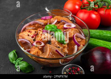 Rohes Schweinefleisch mit Kebab mariniert. Grillfleisch mit Gemüse auf schwarzem Hintergrund. Kochen von Grillgerichten Stockfoto