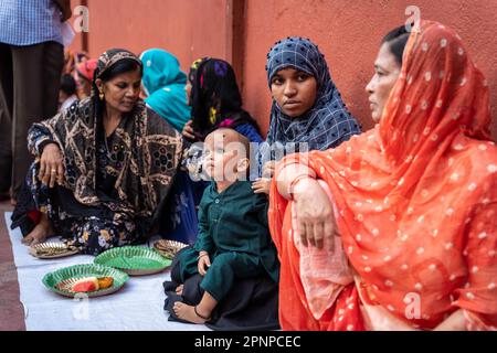 Kalkutta, Indien. 19. April 2023. Ein indischer muslimischer Junge wartet auf das Iftar-Essen (Fast-Breaking-Abendessen von Muslimen), während er auf dem Schoß seiner Mutter in der Nakhoda-Moschee in Kalkutta sitzt. Kredit: SOPA Images Limited/Alamy Live News Stockfoto